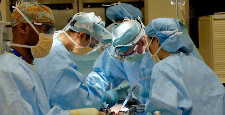 Four people in blue medical scrubs in an operating theatre