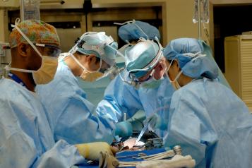 Four people in blue medical scrubs in an operating theatre