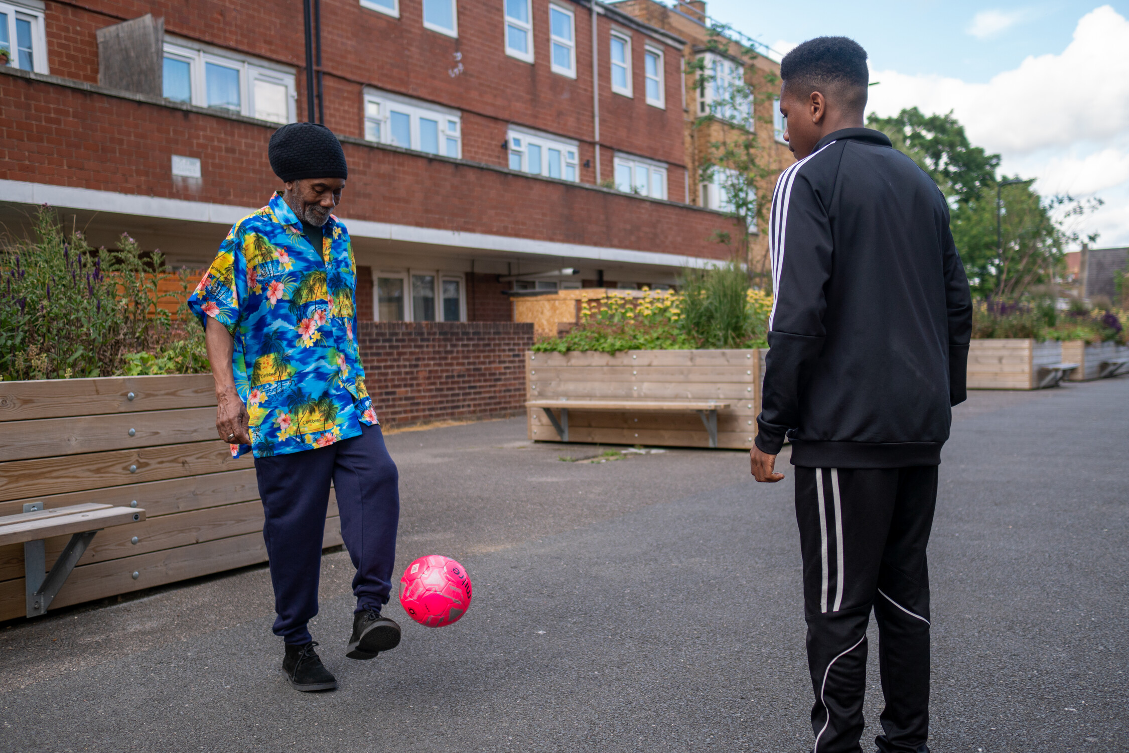 An older man with a teenager kicking a ball outside