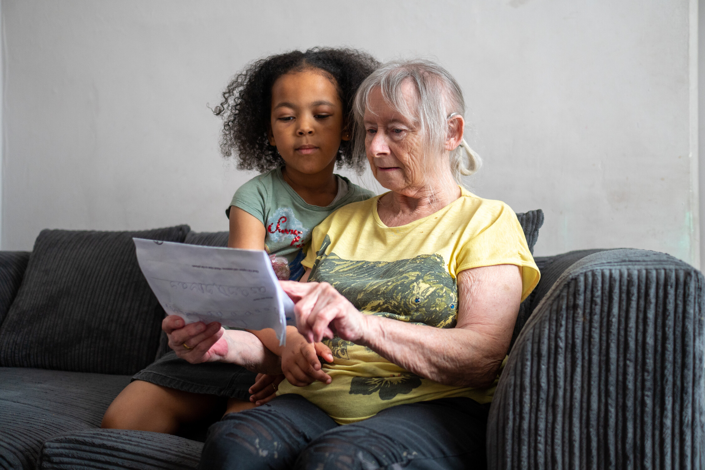 A child reads a book with an older woman 