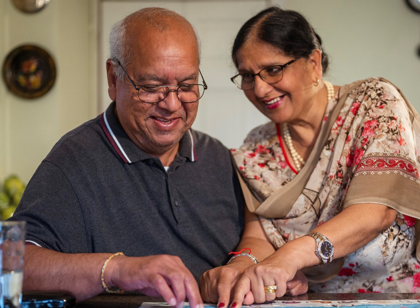 A man and a woman are doing a jigsaw and smiling 