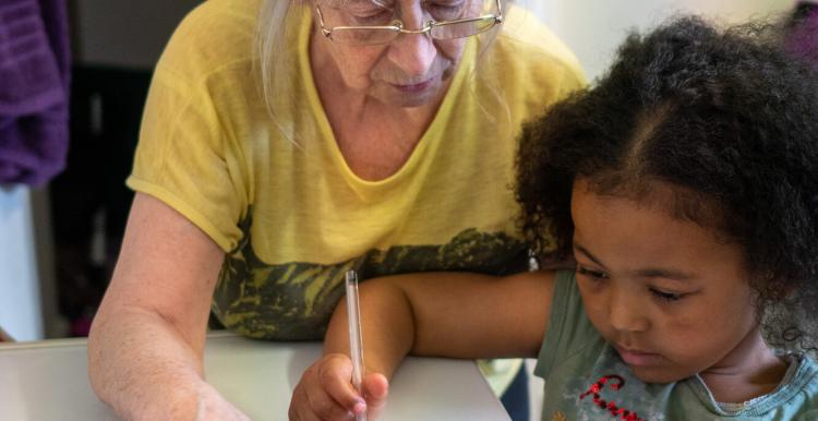 An older woman and young girl colouring at a table