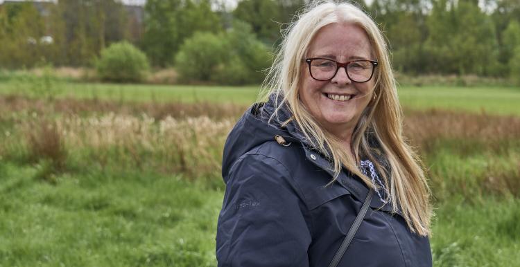A woman standing outside wearing a coat smiling