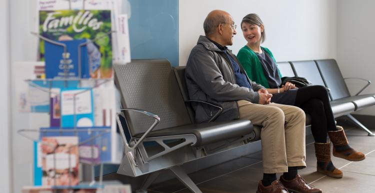 An elderly man and woman sitting in a waiting room
