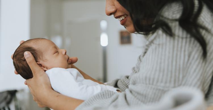 A woman holding a baby and smiling