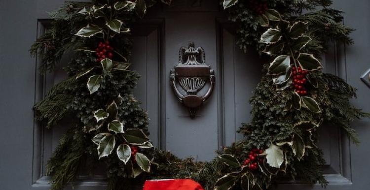 A grey door with a green and red Christmas wreath