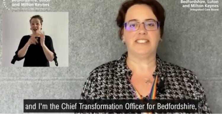 A woman with short brown hair and glasses is talking to the camera, a woman is visible in the top left corner translating into sign language. The subtitles at the bottom read 'I'm in the Chief Transformation Officer for Bedfordshire'