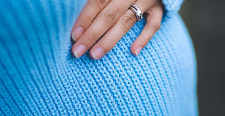 A pregnant woman in a blue jumper 