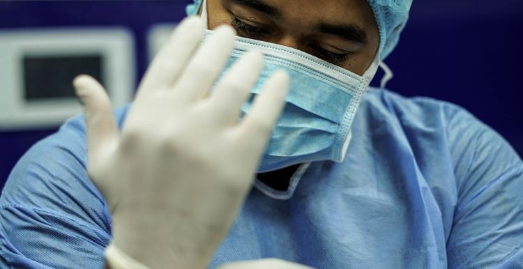 A man wearing surgical scrubs and a mask 