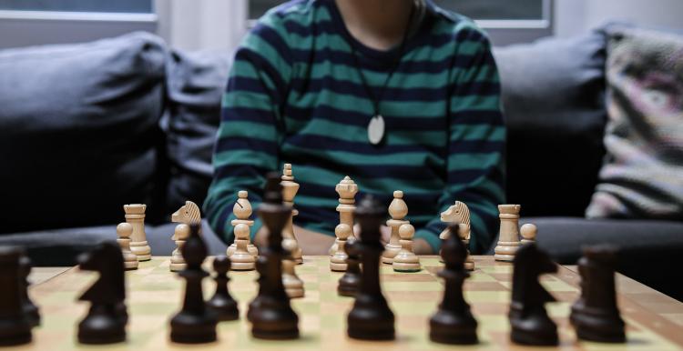 A preteen boy sits in front of a chess board