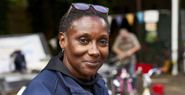 A woman looks at the camera. There is bunting in the background, she is wearing sunglasses on her head 