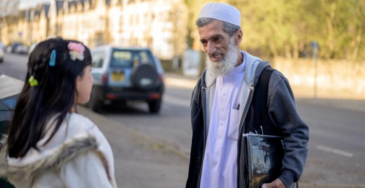 An elderly man chats with a girl outside  