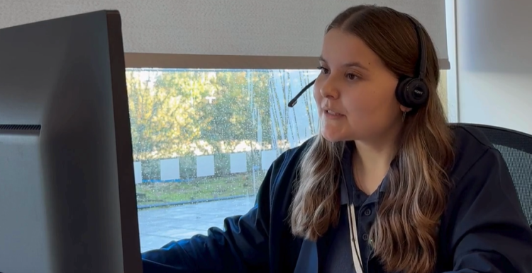 A woman sitting in front of a computer screen talking into a headset