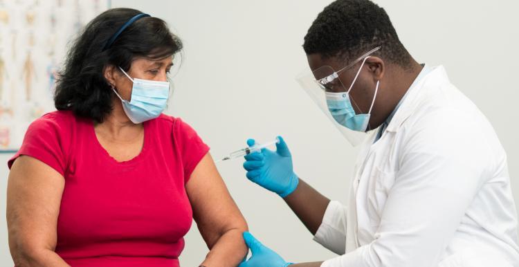 Masked woman getting a vaccine from a doctor 