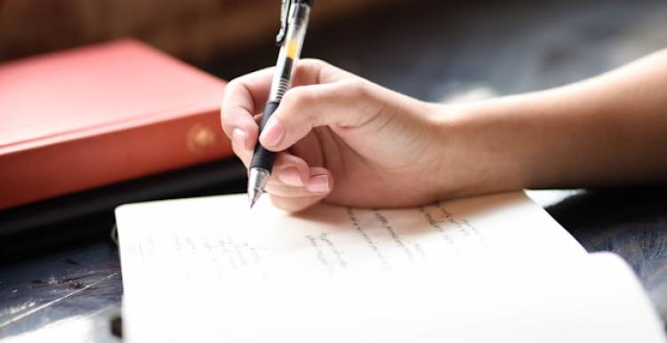 A close up of someone holding a pen and writing in a notebook