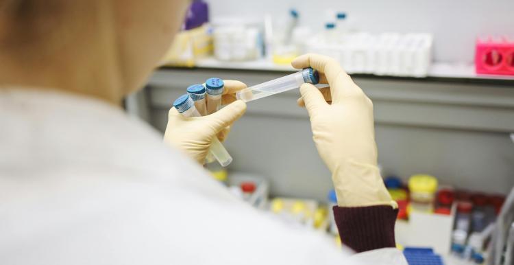Close up of a person wearing a white lab coat holding a test tube