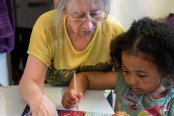 An older woman and young girl colouring at a table 