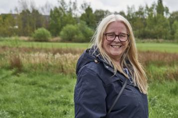 A woman standing outside wearing a coat smiling 