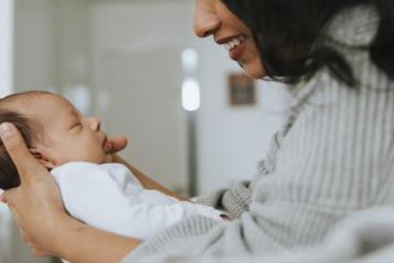 A woman holding a baby and smiling 