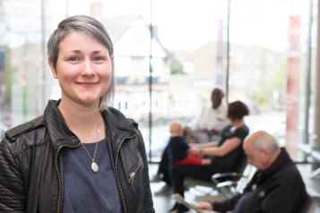 A woman with short blonde hair stands in a waiting room