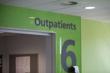 Green wall with grey signage reading 'Level 6. Outpatients' 