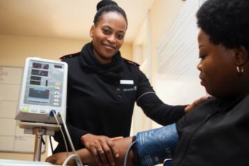 A woman sits in a chair and has her blood pressure taken 