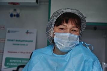 A female patient in a mask and scrubs in a hospital 