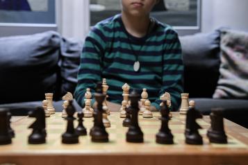 A preteen boy sits in front of a chess board