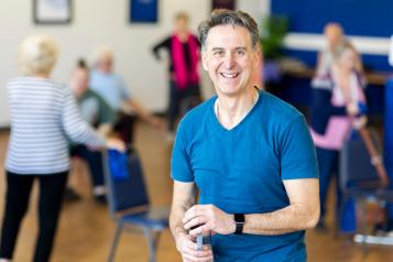 A man in a blue t shirt smiles at the camera