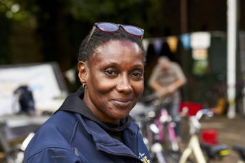 A woman looks at the camera. There is bunting in the background, she is wearing sunglasses on her head 