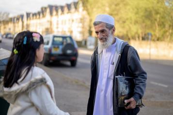 An elderly man chats with a girl outside  