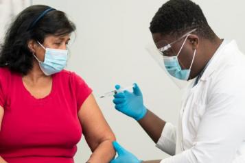 Masked woman getting a vaccine from a doctor 