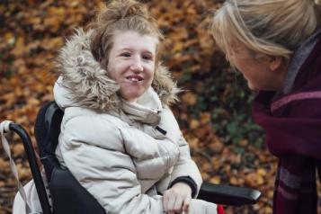 Young woman wearing a winter coat sitting in a wheelchair outside. 