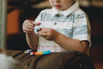 A  pre-school aged boy sits and plays lego 