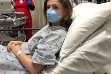 A patient in a hospital bed wearing a mask