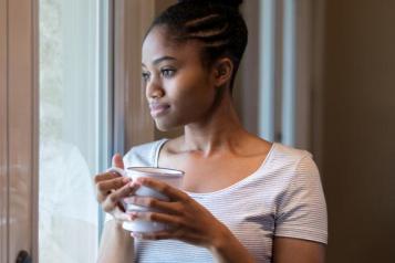 Woman standing by a window holding a mug