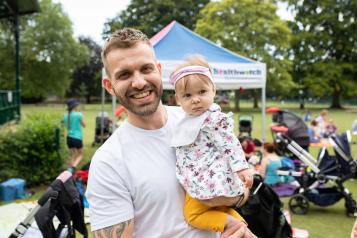 Man holding a baby outside and smiling