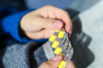 A close up of hands holding a blister pack of yellow pills