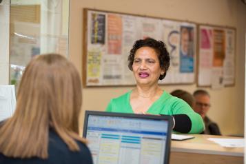 A woman stands in front of a reception desk 