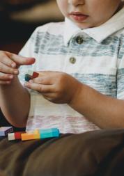 A  pre-school aged boy sits and plays lego 