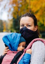 Mum wearing a mask carrying a baby in a sling 